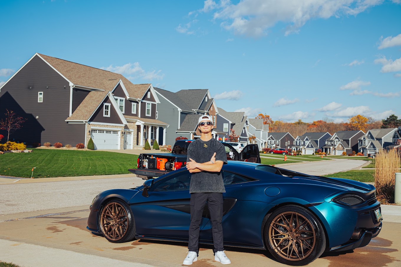 Jacob Corso with the Elevare mobile detailing rig beside a blue McLaren in a client's driveway